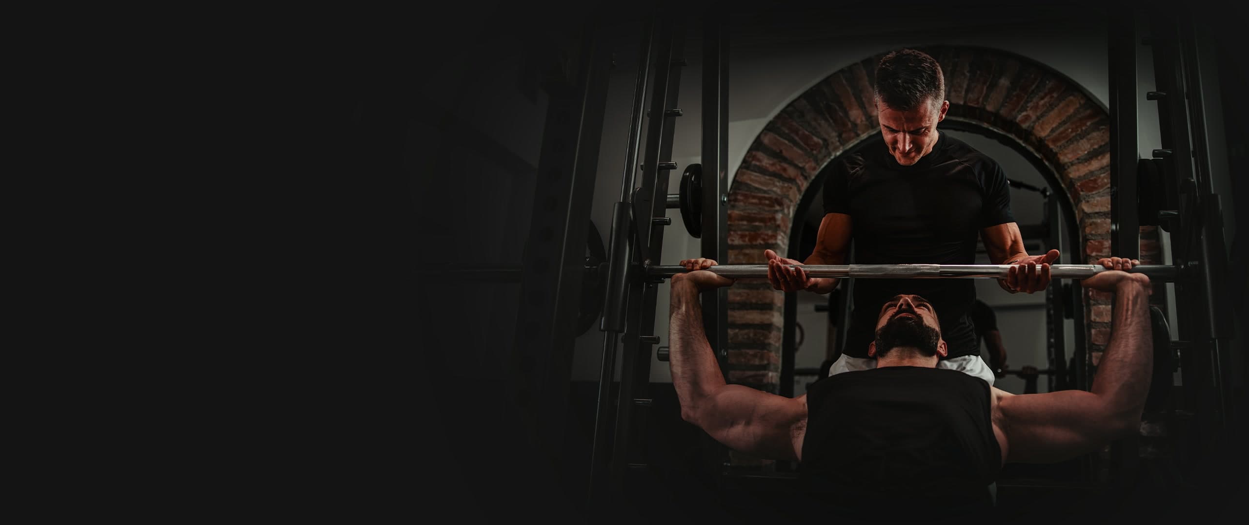 A SENA coach spotting a client through a barbell bench press